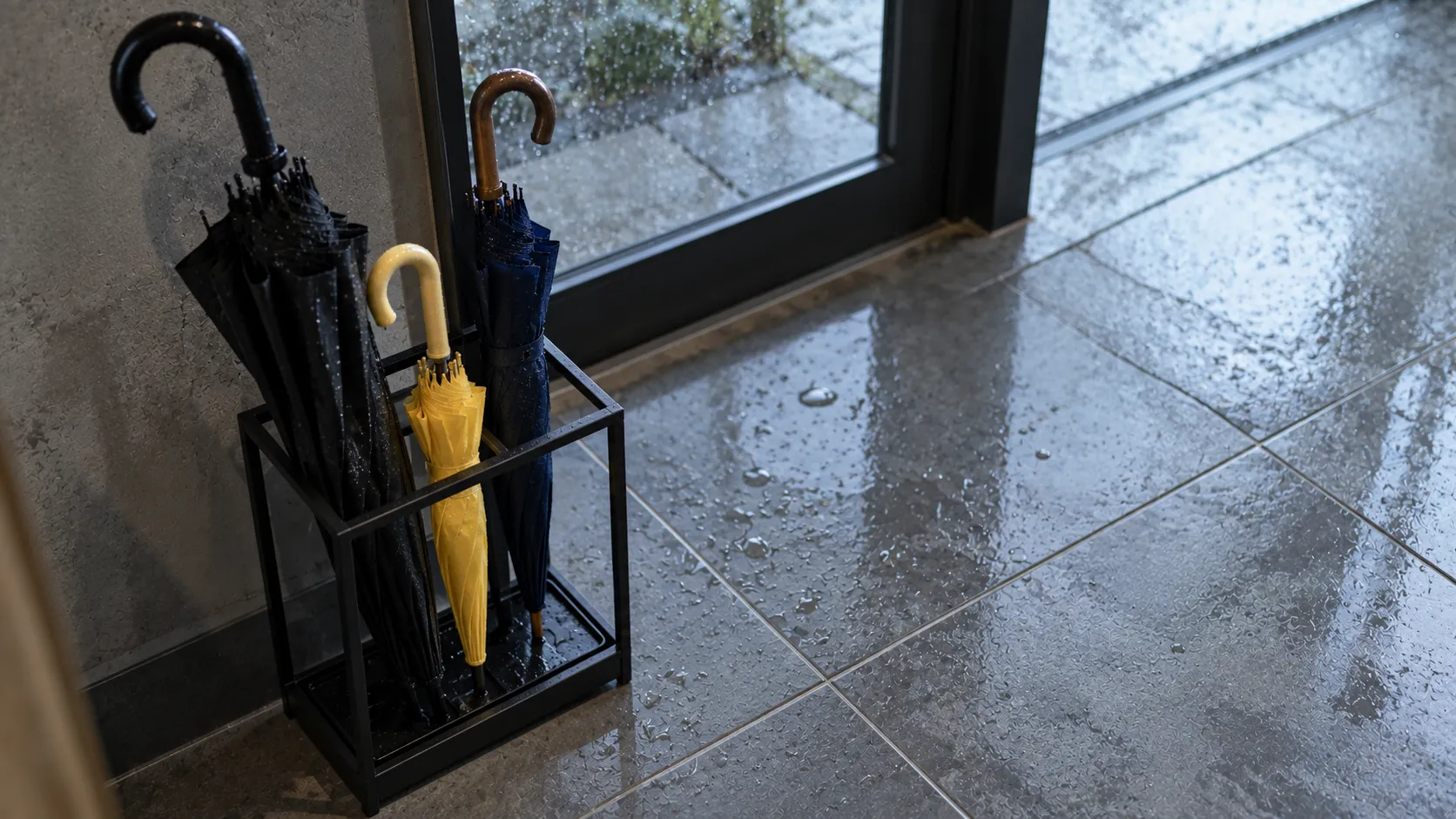 雨の日の入口の傘立てに並ぶ大人用と子ども用の傘