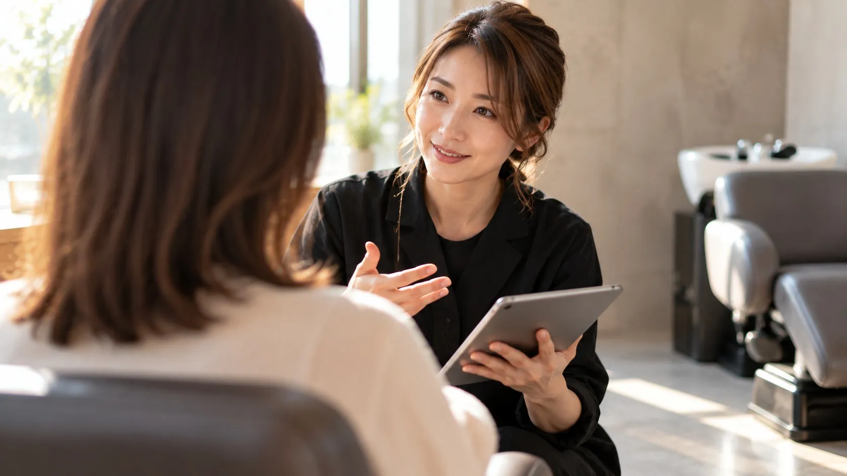 一人のお客様に正面から向き合う女性スタイリストを肩越しに捉えた図